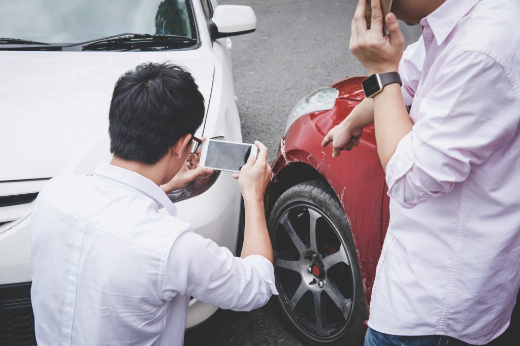 Two drivers man arguing after a car traffic accident collision and making phone call to Insurance